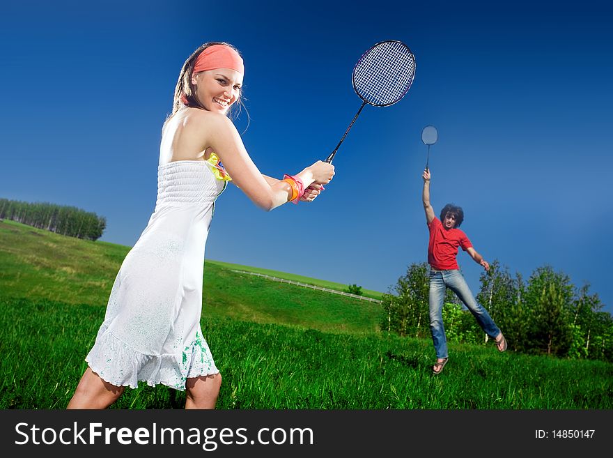 Boy and nice girl with rackets on field