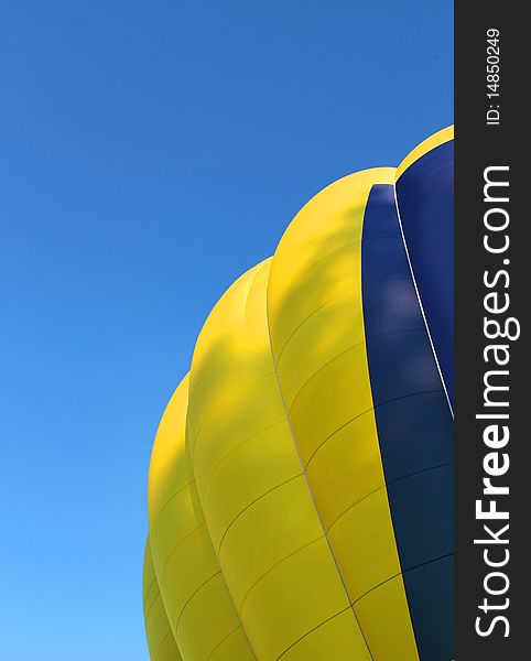 Yellow and blue hot air balloon on bright blue sky background. Yellow and blue hot air balloon on bright blue sky background