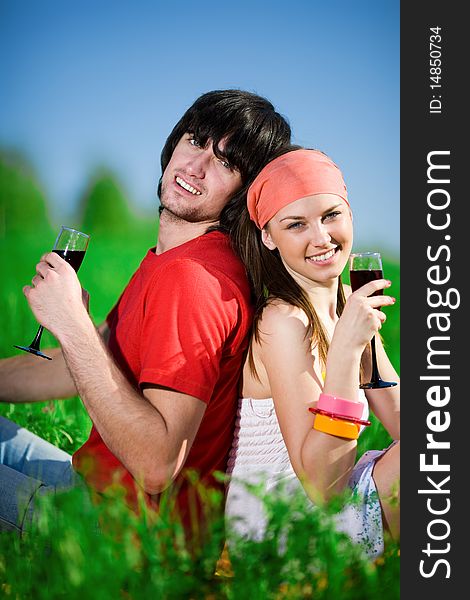 Smiling girl and boy with wineglasses on grass