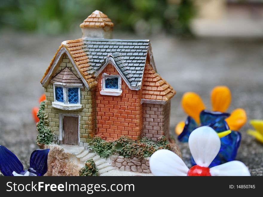 Picture of a miniature house surrounded by glass flowers.