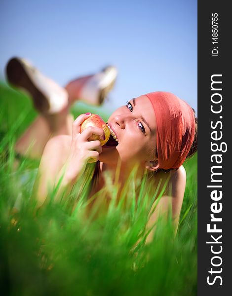 Girl in kerchief with apple on grass