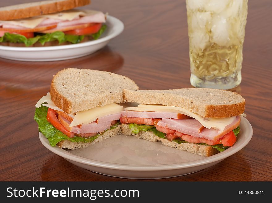 Ham and swiss cheese sandwich with tomato and lettuce on rye bread with a drink. Ham and swiss cheese sandwich with tomato and lettuce on rye bread with a drink