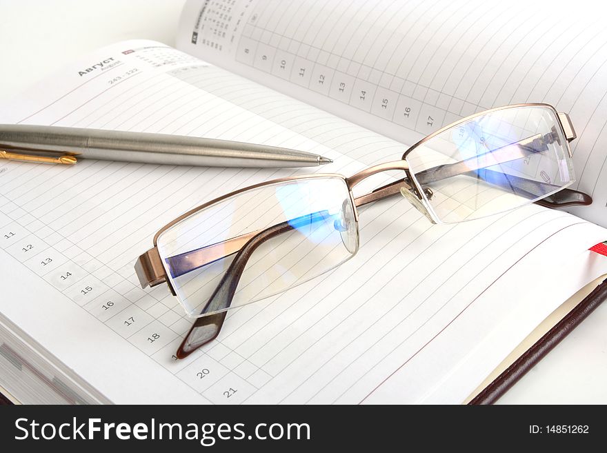 Notebook, pen and eyeglasses on white background