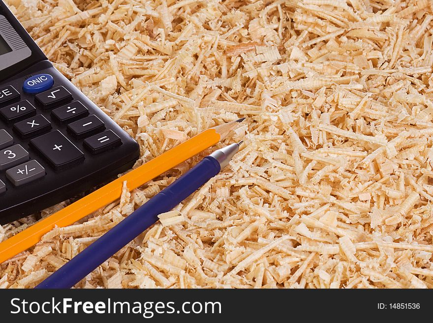 Calculator and pencil at wooden shaving