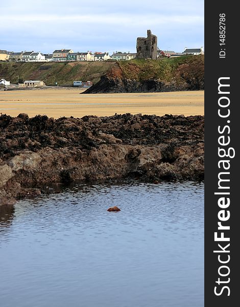 The old ruin of a castle in ballybunion overlooking the beach with black rocks in foreground. The old ruin of a castle in ballybunion overlooking the beach with black rocks in foreground