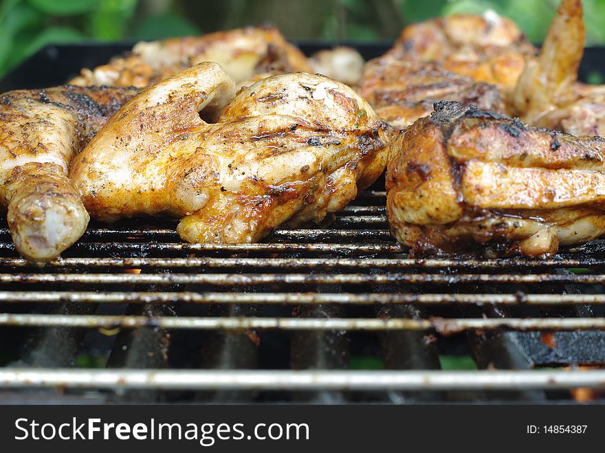 Pieces of chicken on metal grill. Pieces of chicken on metal grill