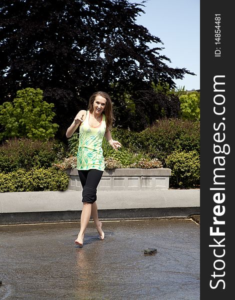 A woman having fun running in the park through some water with splashing and smiling. A woman having fun running in the park through some water with splashing and smiling.