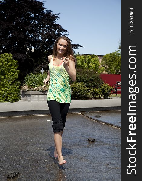 A woman in a park in the city running and cooling off with a smile on her face. A woman in a park in the city running and cooling off with a smile on her face.