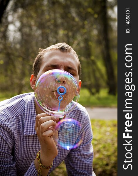 Young guy in the park blow bubbles