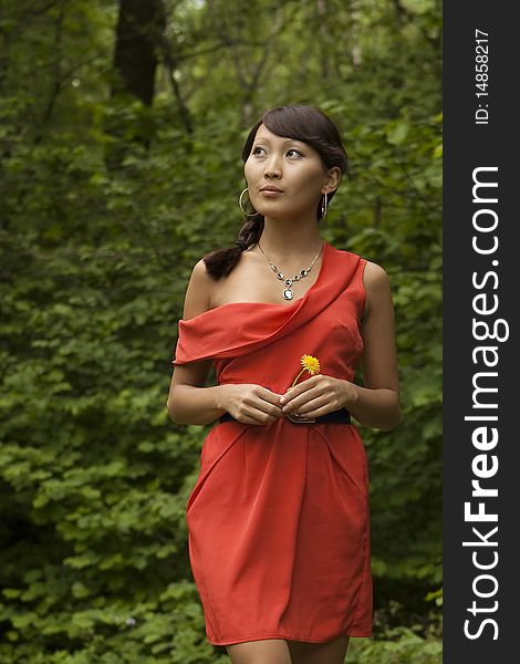 Beautiful Asian in a red dress walking through the park. Beautiful Asian in a red dress walking through the park