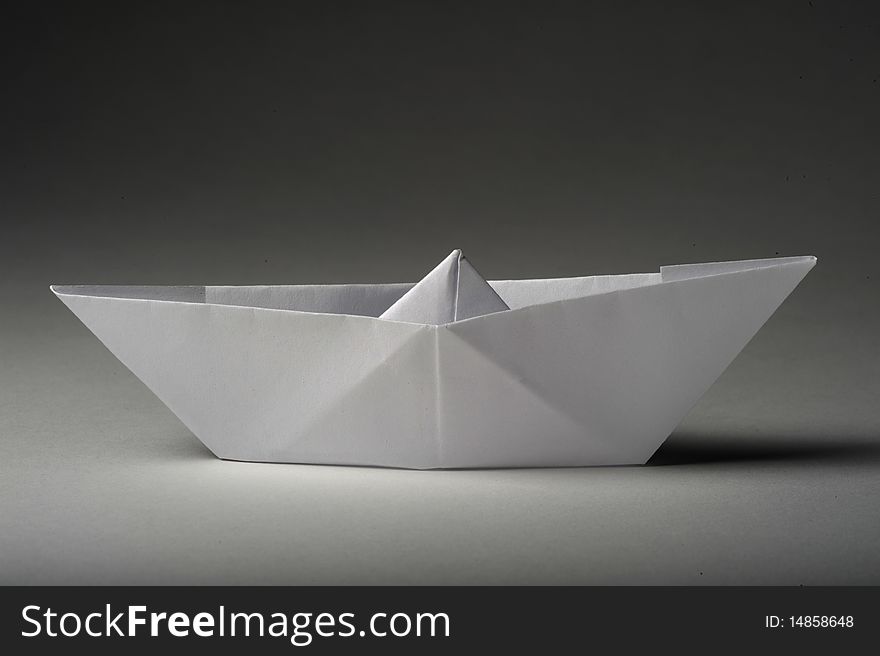A toy paperboat. White paper. Some shadows.