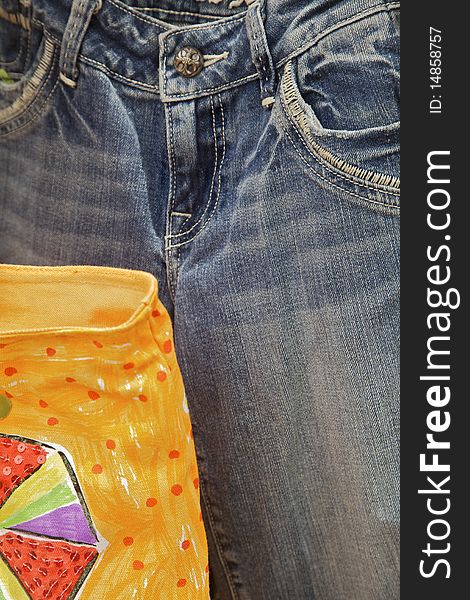 Pair of blue jeans with part of yellow shopping bag. Vertical shot. Pair of blue jeans with part of yellow shopping bag. Vertical shot.