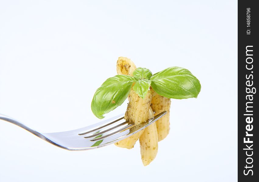 Penne with pesto on a fork decorated with basil