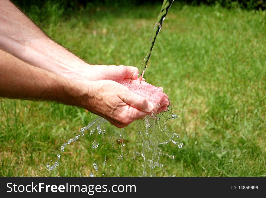 Man's cupped hands full to overflowing with fresh water. Man's cupped hands full to overflowing with fresh water