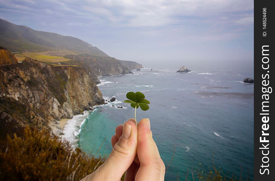 Good luck background. Hand holding leaf clover. Irish cliffs background