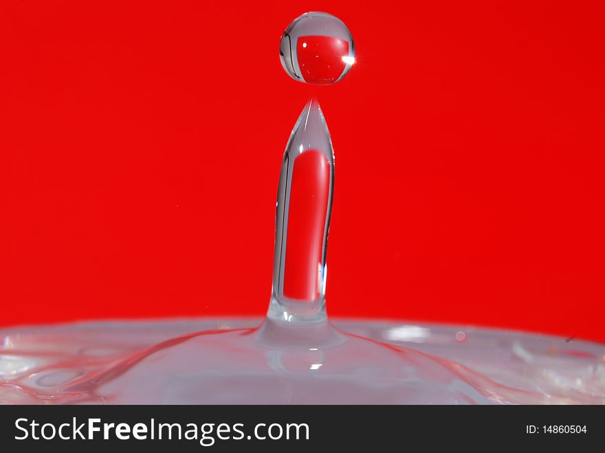 Water drop splashed with red background.