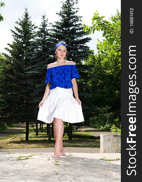 Young girl in blue blouse and white skirt posing outdoors. Young girl in blue blouse and white skirt posing outdoors