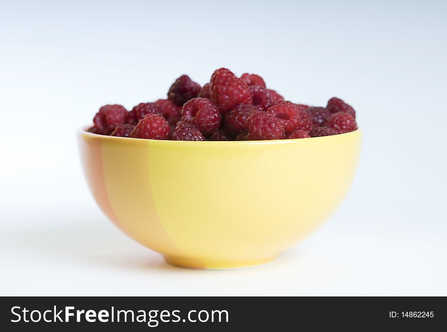 Orange plate full of red raspberries on white background. Orange plate full of red raspberries on white background