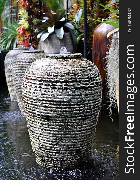 Terracotta Pottery in a water ditch with colorful plants in the background