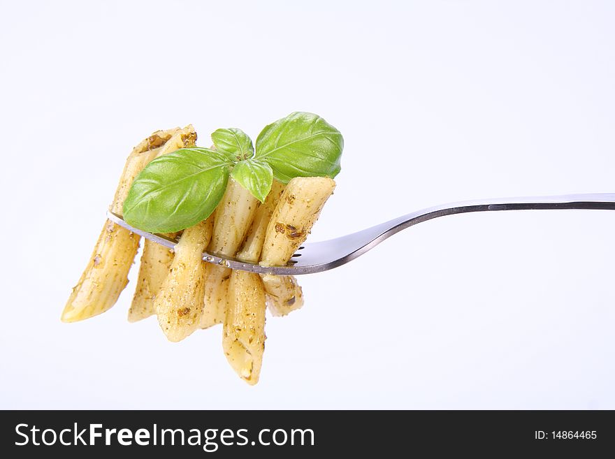 Penne with pesto on a fork decorated with basil