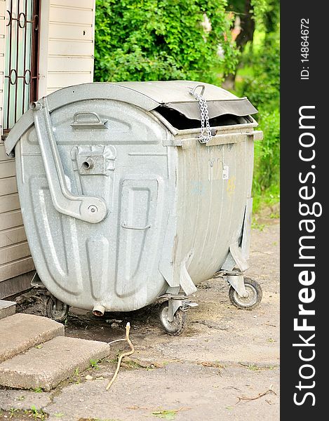 The photo shows a rubbish, rubbish container on a closed chain with a padlock. The photo shows a rubbish, rubbish container on a closed chain with a padlock.