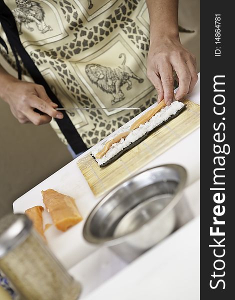 A sushi chef in action preparing a sushi dish with salmon