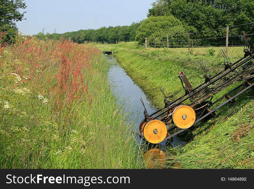 Mowing shore side of a ditch for flow and abduction of water. Mowing shore side of a ditch for flow and abduction of water