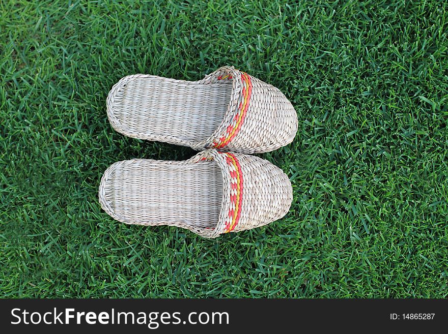Footwear hand made from straw on the green grass. Footwear hand made from straw on the green grass