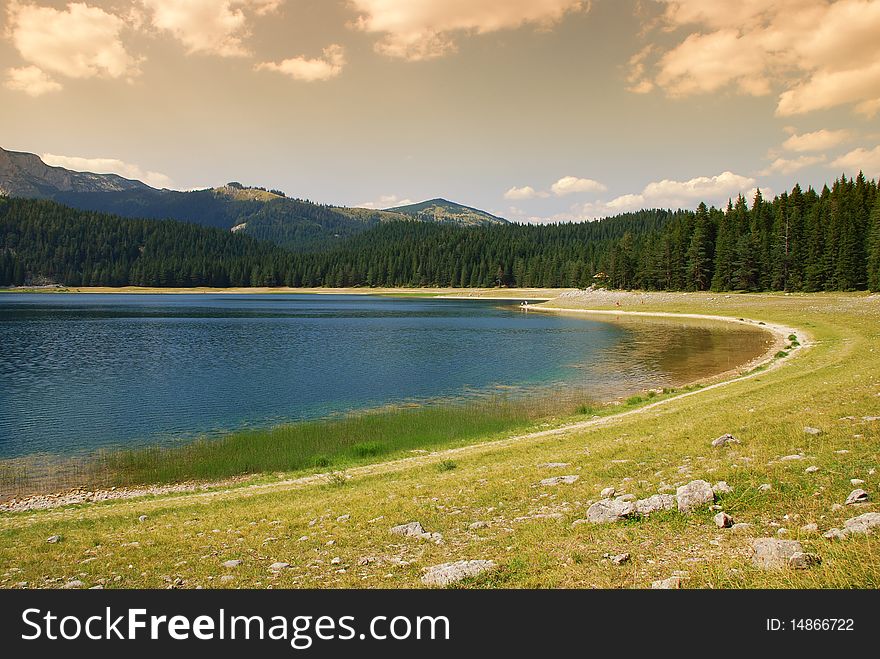 Mountain lake pine forest and clouds