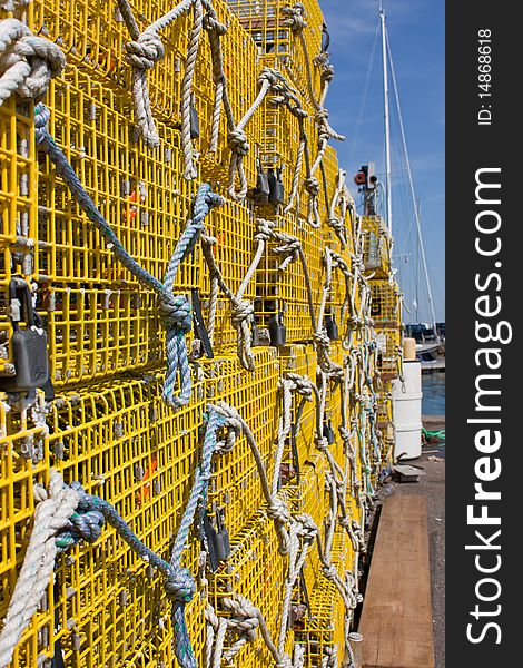 Large stack of yellow commercial lobster traps with a boats mast in the background. Large stack of yellow commercial lobster traps with a boats mast in the background