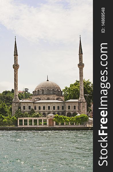 A mosque on the edge of a large river against a blue sky. A mosque on the edge of a large river against a blue sky