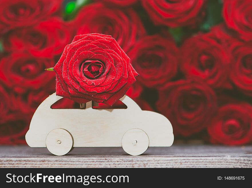 Concept of flower delivery, love, typewriter transports a flower against a background of red roses