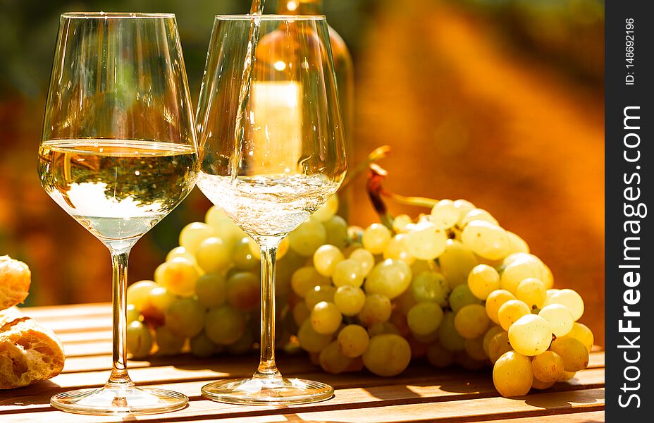 Glass of dry White wine ripe grapes and bread on table in vineyard