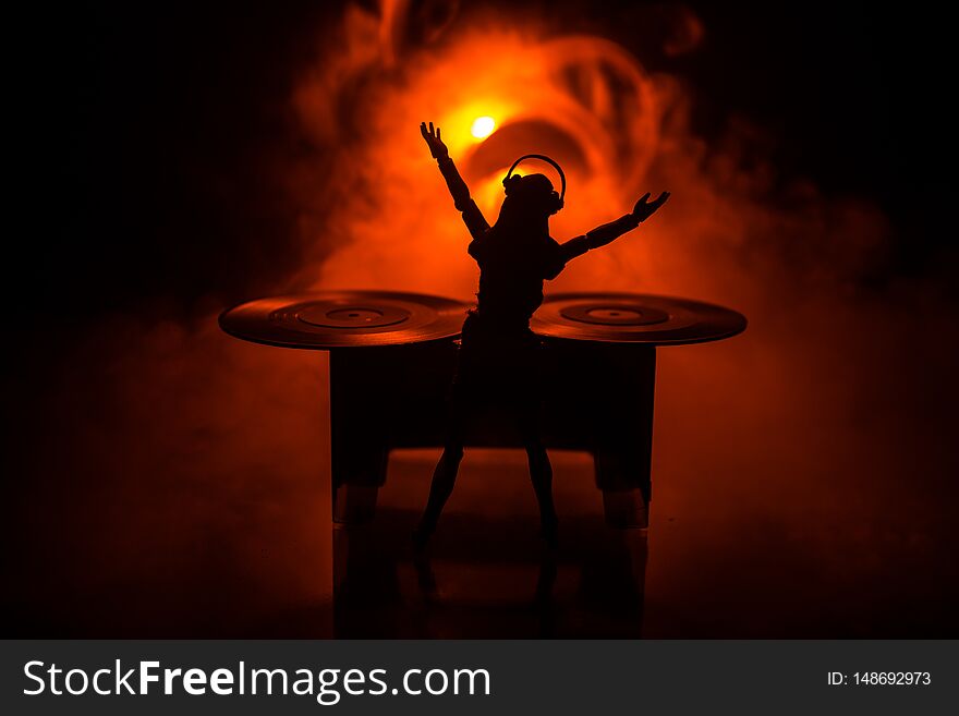 Dj club concept. Woman DJ mixing, and Scratching in a Night Club. Girl silhouette on dj s deck, strobe lights and fog on