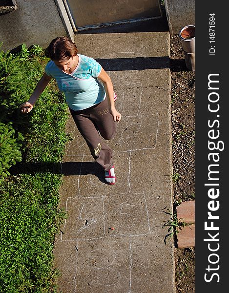 Girl hopping on a hopscotch game painted on pavement. Girl hopping on a hopscotch game painted on pavement