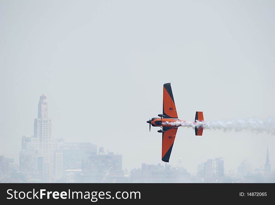 Colorful plane performing acrobatics against the backdrop of New York City skyline. Colorful plane performing acrobatics against the backdrop of New York City skyline