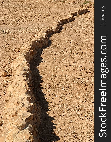 Curved wall of ancient fortress ruin in yellow desert