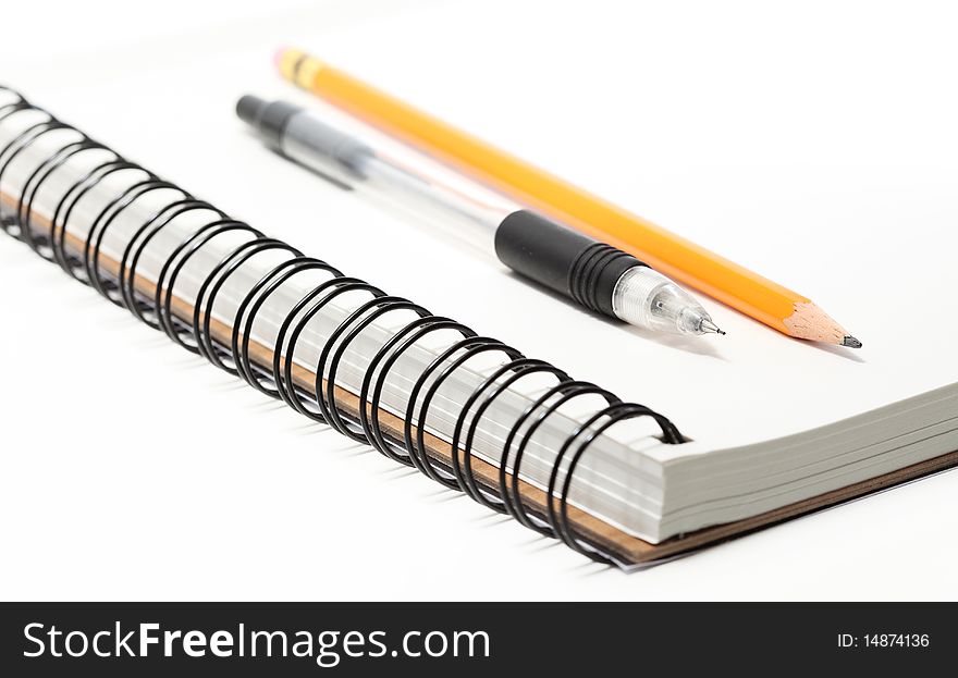A spiral sketchbook or notepad with one mechanical and one standard pencil on top, closeup. A spiral sketchbook or notepad with one mechanical and one standard pencil on top, closeup