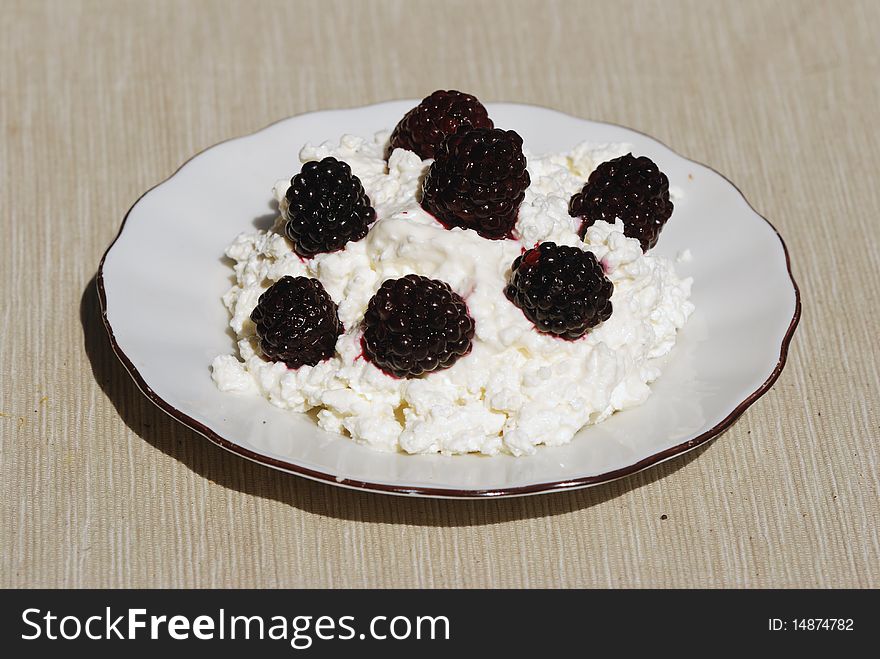 Plate of cottage cheese with blackberry  on gray  napkin