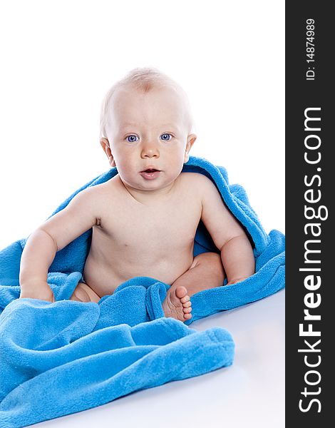 Beautiful baby under a blue towel on white background