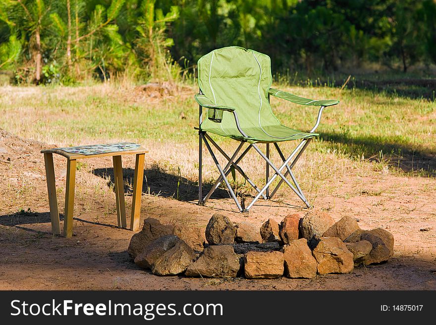 Folding chair and table next to a fire ring. Folding chair and table next to a fire ring.