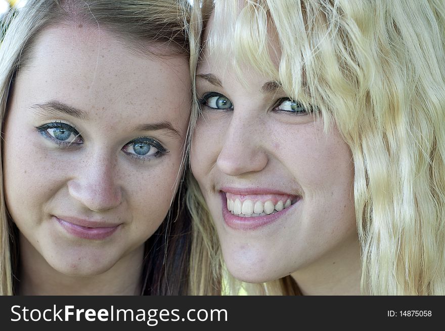 Closeup photograph of two pretty blond girl friends smiling at the camera. Closeup photograph of two pretty blond girl friends smiling at the camera.