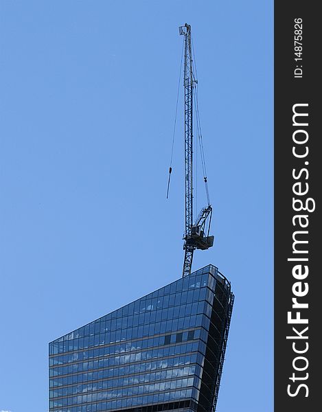 Construction crane at the windows of a skyscraper backdrop of glass and concrete