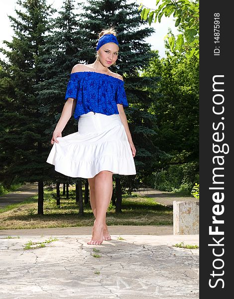 Pretty young woman in blue blouse and white skirt with bare feet. Pretty young woman in blue blouse and white skirt with bare feet