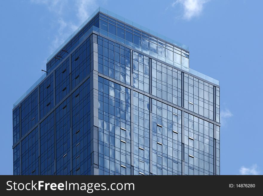 Reflection of a cloudy sky in glass wall of an office building