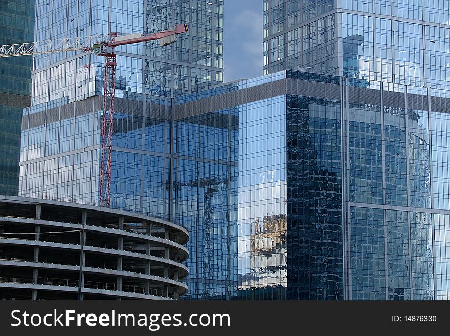 Construction crane at the windows of a skyscraper backdrop of glass and concrete