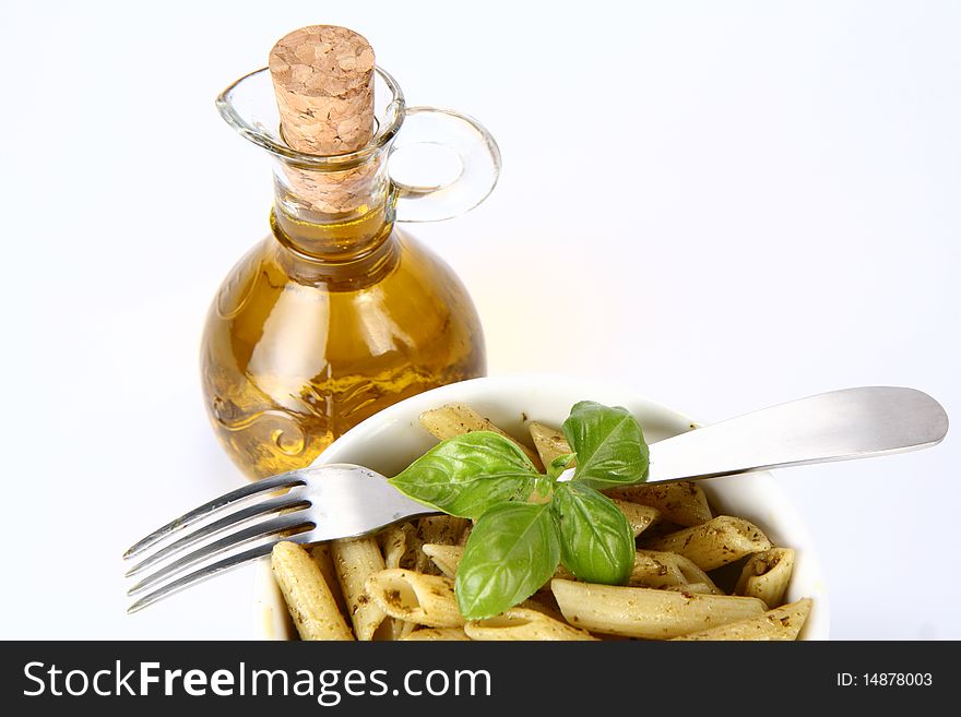 Penne with pesto in  a bowl and olive oil in a bottle. Penne with pesto in  a bowl and olive oil in a bottle