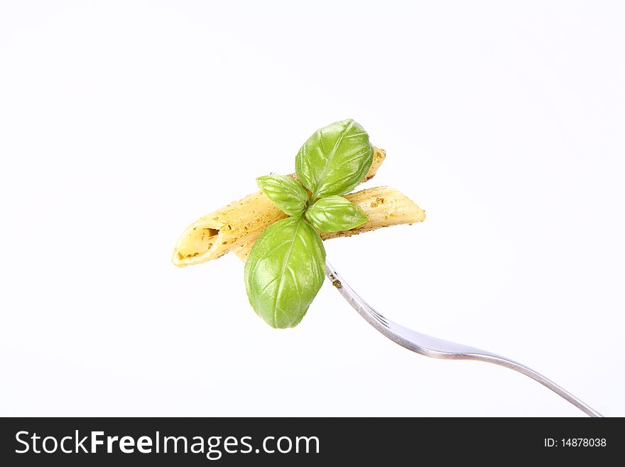 Penne with pesto on a fork decorated with basil