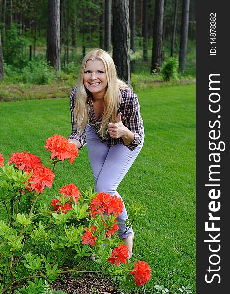 Beautiful gardener woman with red flower bush outdoors