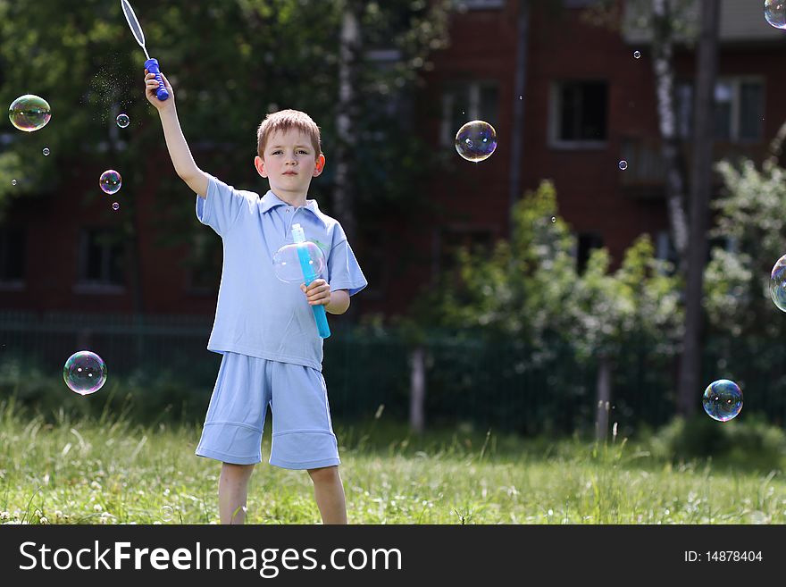 Little boy is played with soap bubbles in the street